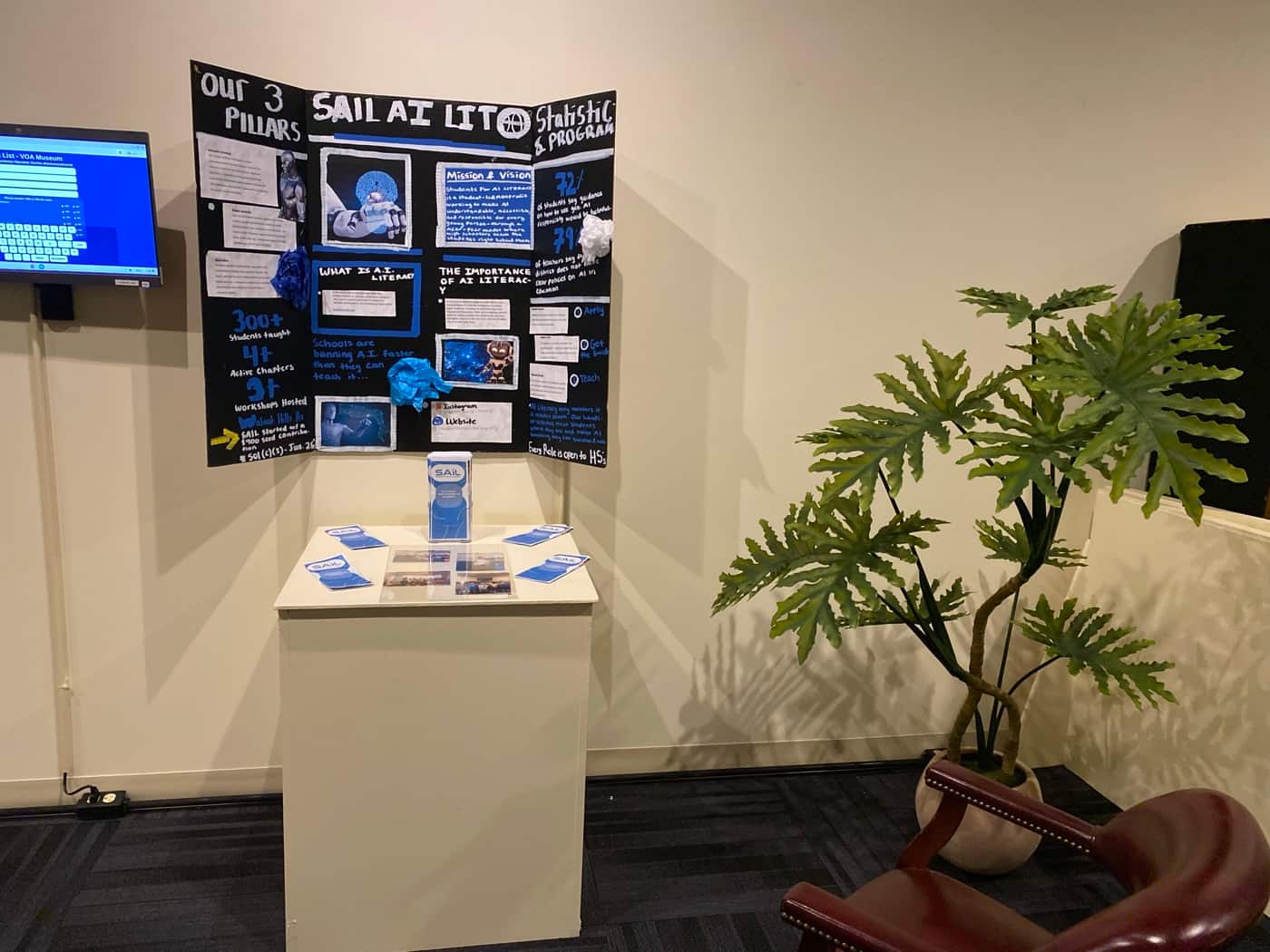 The SAIL display in a museum gallery, with the poster board mounted above a plinth of brochures
